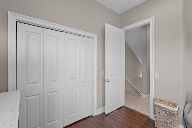 bedroom featuring dark wood-type flooring, a closet, and a textured ceiling