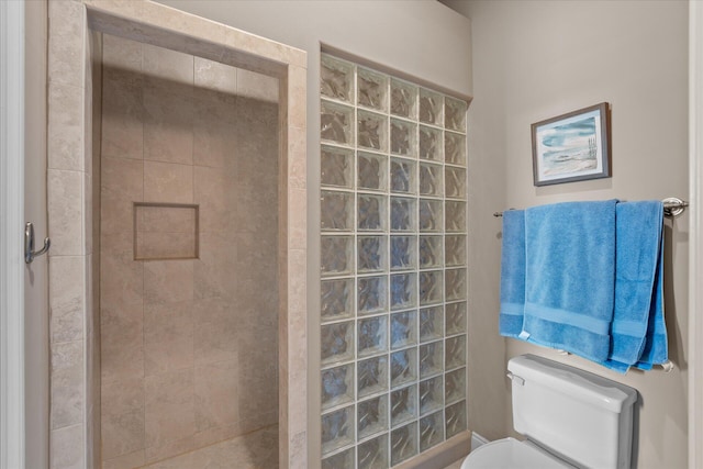 bathroom featuring a tile shower and toilet