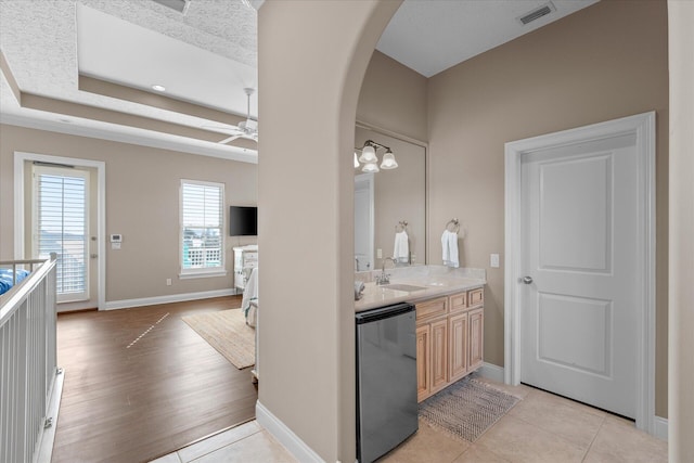 bathroom featuring a raised ceiling, vanity, tile patterned flooring, and ceiling fan