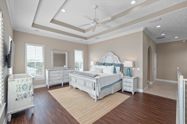 bedroom with dark hardwood / wood-style floors, ceiling fan, a tray ceiling, crown molding, and a textured ceiling