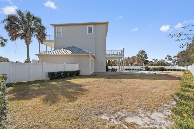 rear view of property featuring a patio, a balcony, and a lawn