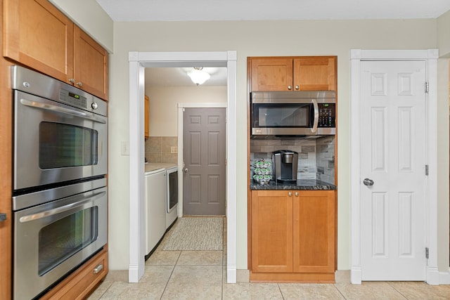 kitchen with stainless steel appliances, tasteful backsplash, light tile patterned floors, and washer and clothes dryer