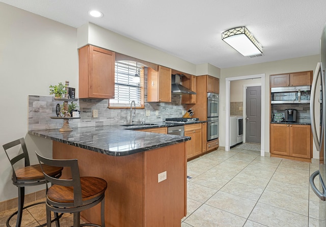 kitchen with sink, wall chimney range hood, a breakfast bar area, stainless steel appliances, and kitchen peninsula