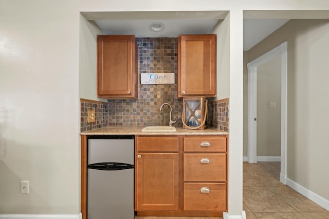 kitchen with light tile patterned flooring, sink, stainless steel fridge, and decorative backsplash