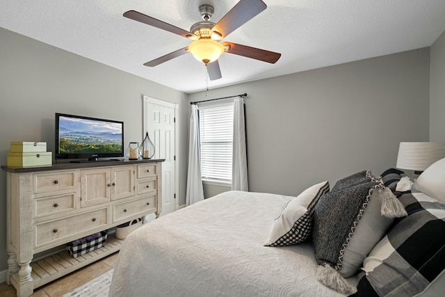 tiled bedroom with ceiling fan and a textured ceiling