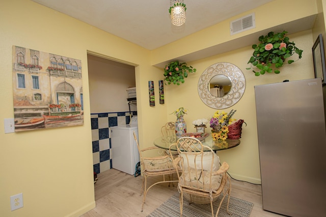 dining area featuring washing machine and dryer and light wood-type flooring