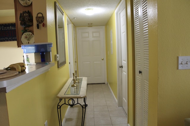 hall featuring a textured ceiling and light tile patterned floors