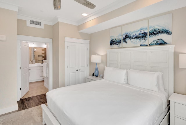 bedroom with hardwood / wood-style flooring, ornamental molding, and connected bathroom