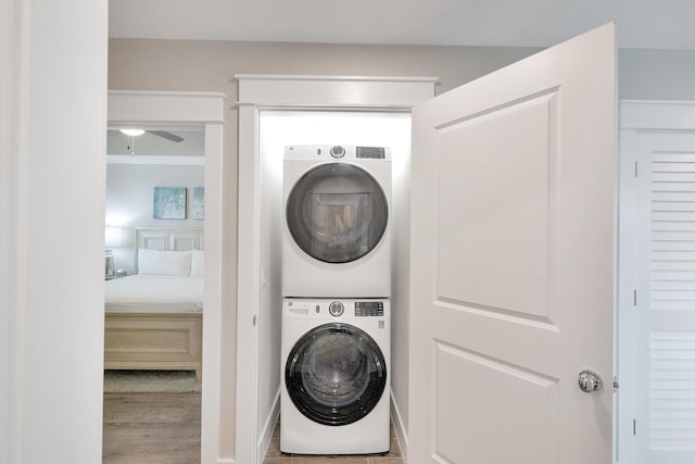 laundry room with stacked washer / drying machine, ceiling fan, and light hardwood / wood-style flooring