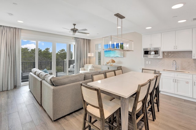 dining space with sink, light hardwood / wood-style flooring, and ceiling fan