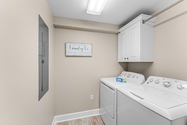 clothes washing area with electric panel, cabinets, washing machine and clothes dryer, and light wood-type flooring