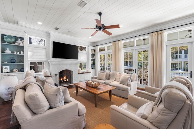 living room featuring a brick fireplace, wooden ceiling, built in shelves, and visible vents