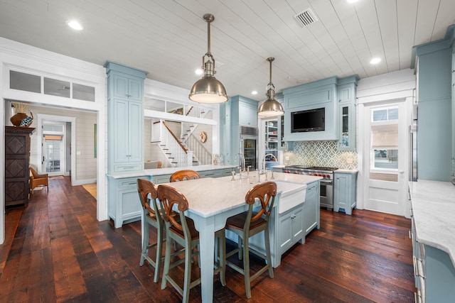 kitchen featuring dark wood-style flooring, tasteful backsplash, an island with sink, and visible vents