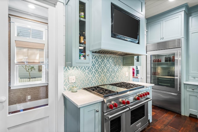 kitchen featuring dark wood-style floors, tasteful backsplash, light countertops, high quality appliances, and extractor fan