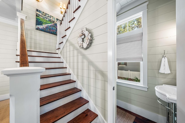 staircase featuring baseboards and wooden walls