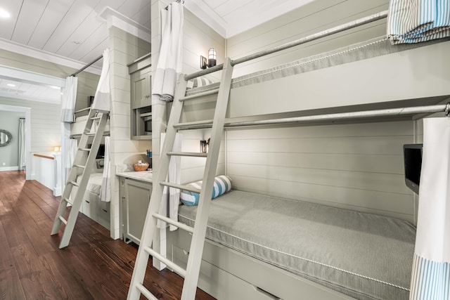 bedroom with wood walls, dark wood finished floors, wood ceiling, and crown molding