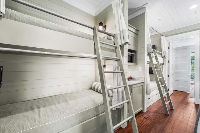 bedroom with wood walls and dark wood-style flooring