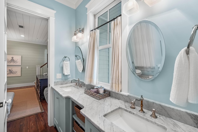 full bathroom featuring double vanity, visible vents, a sink, and wood finished floors