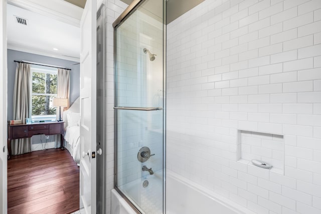 full bath featuring ornamental molding, enclosed tub / shower combo, visible vents, and wood finished floors