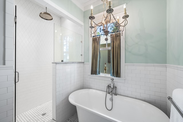 bathroom featuring a wainscoted wall, tile walls, a soaking tub, a shower stall, and an inviting chandelier