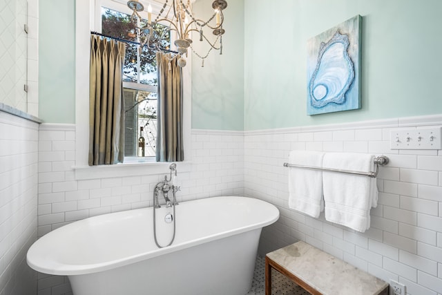 full bath featuring wainscoting, a freestanding tub, tile walls, and a healthy amount of sunlight