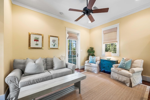 living area with light wood-style floors, baseboards, ornamental molding, and ceiling fan