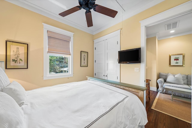 bedroom featuring attic access, baseboards, visible vents, ornamental molding, and wood finished floors