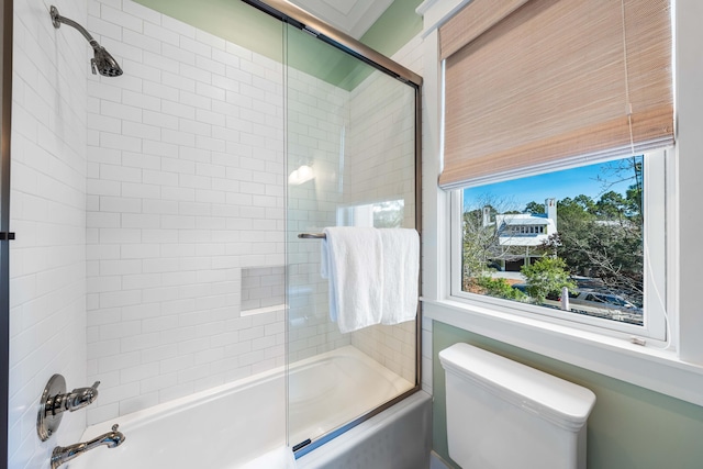 bathroom with toilet and bath / shower combo with glass door