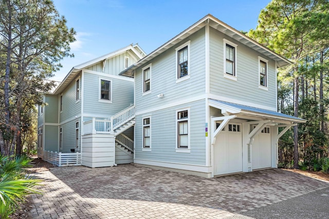 view of front of house with stairway, board and batten siding, an attached garage, and decorative driveway