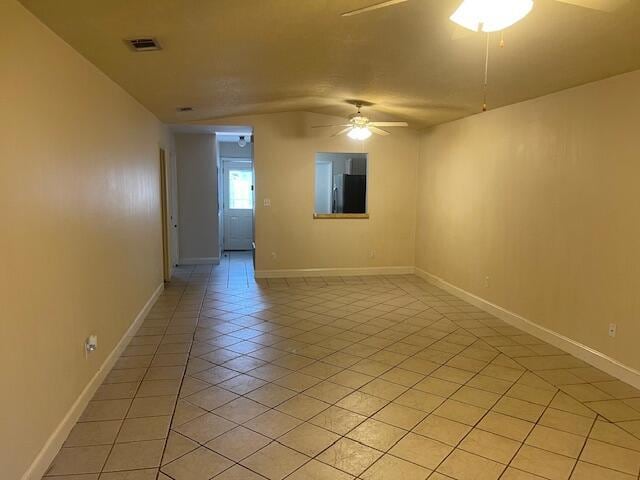 tiled spare room with ceiling fan