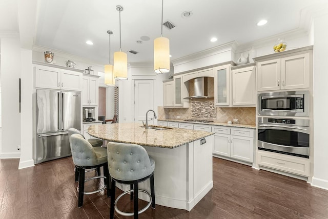 kitchen with visible vents, dark wood-type flooring, wall chimney range hood, stainless steel appliances, and a sink