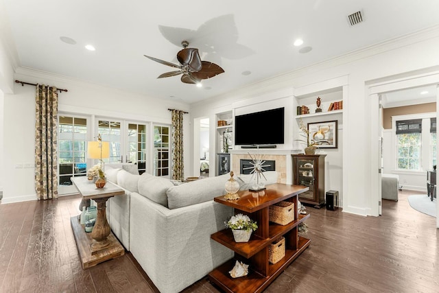 living room with a ceiling fan, visible vents, baseboards, dark wood-style flooring, and crown molding