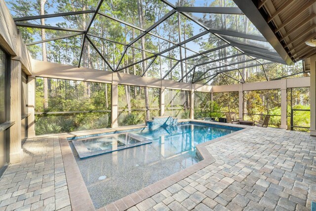 view of pool with glass enclosure, a patio area, and a pool with connected hot tub