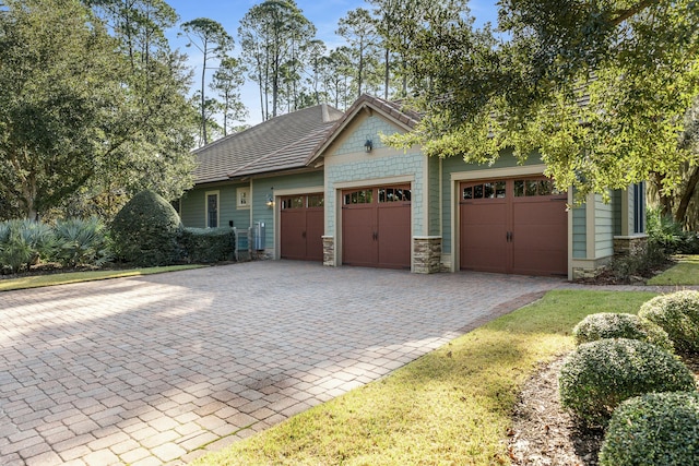 craftsman-style house with decorative driveway, an attached garage, and stone siding