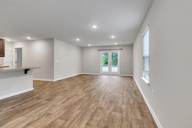 unfurnished living room featuring french doors and light wood-type flooring