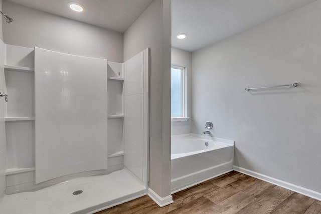 bathroom with wood-type flooring and shower with separate bathtub