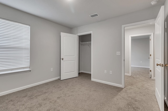 unfurnished bedroom with light colored carpet and a closet