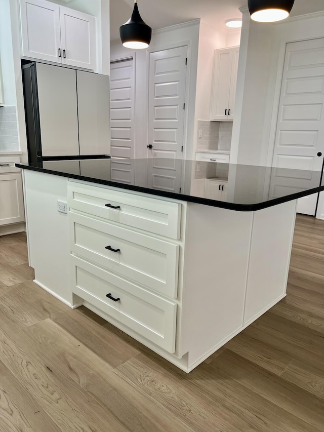 kitchen featuring light wood-type flooring, white cabinetry, refrigerator, and decorative backsplash