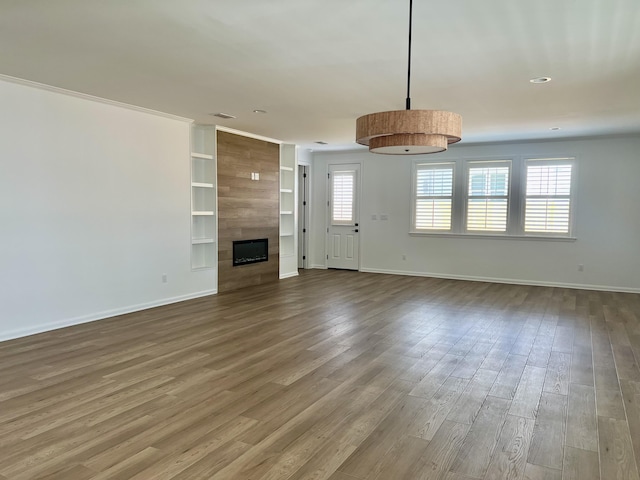 unfurnished living room featuring a fireplace, hardwood / wood-style floors, and built in shelves