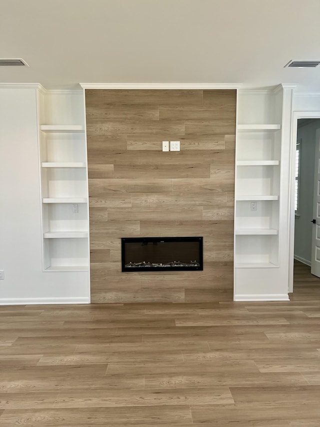 unfurnished living room featuring a large fireplace, hardwood / wood-style floors, and built in features