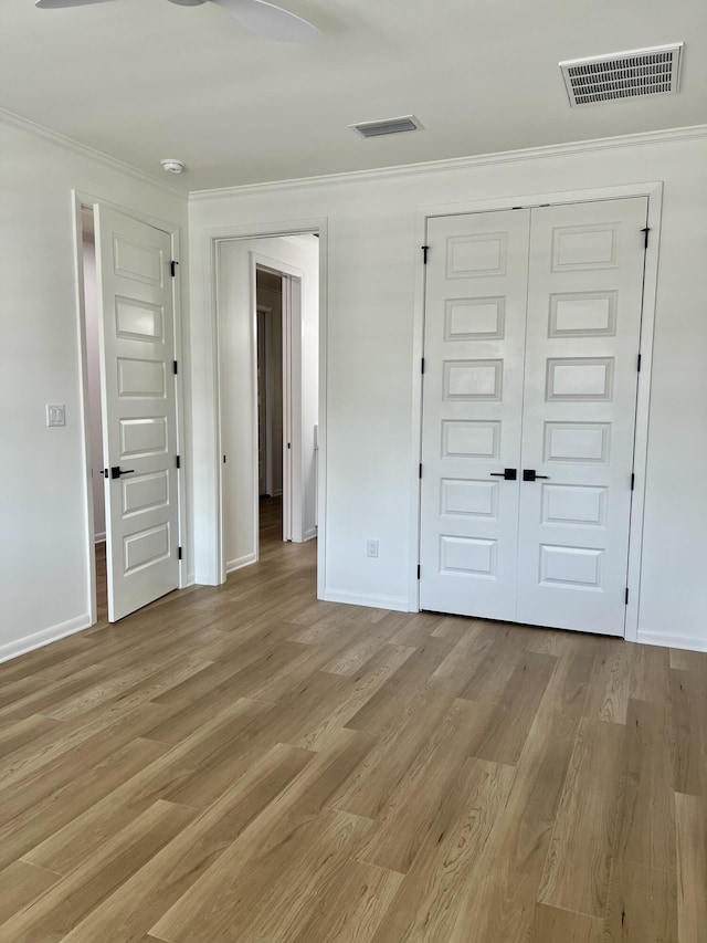 unfurnished bedroom with light hardwood / wood-style floors, a closet, and crown molding