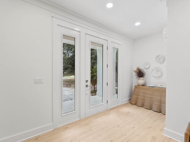 doorway to outside featuring ornamental molding and light wood-type flooring