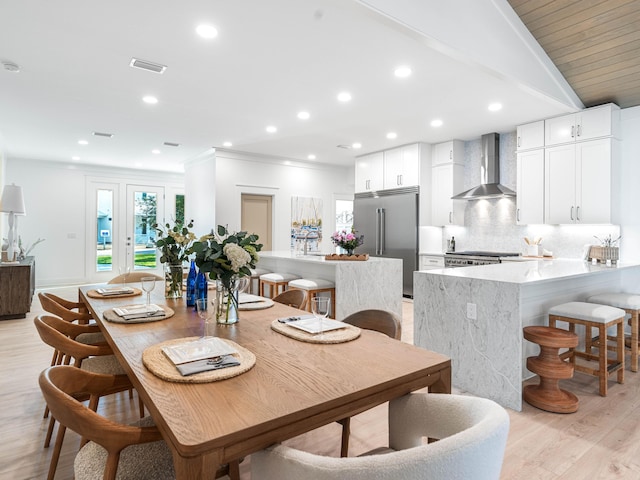 dining room with ornamental molding and light hardwood / wood-style flooring