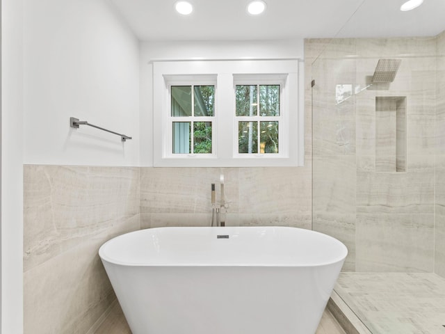 bathroom featuring tile walls and independent shower and bath