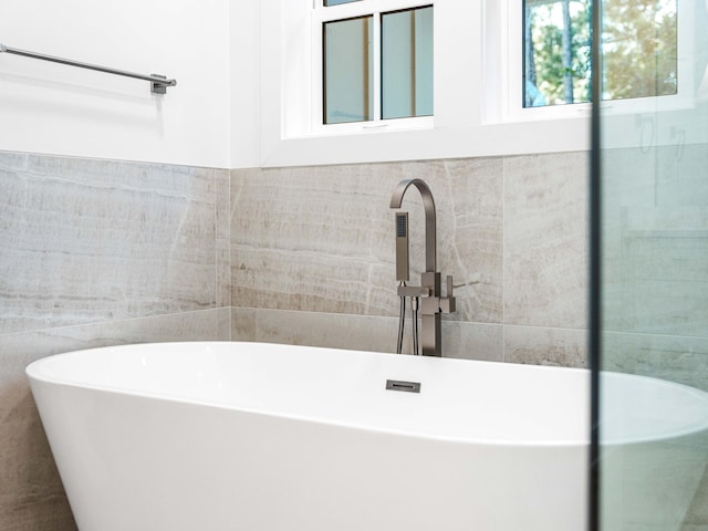 bathroom with a tub and tile walls