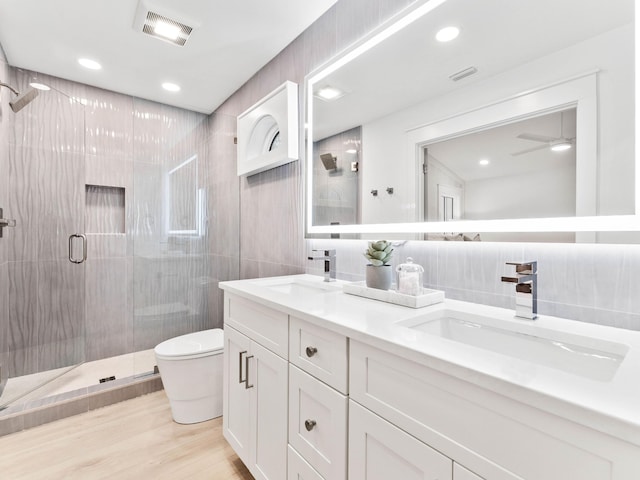 bathroom featuring a shower with shower door, tile walls, vanity, toilet, and hardwood / wood-style flooring