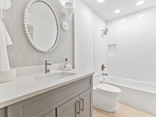 full bathroom featuring toilet, vanity, tiled shower / bath, and wood-type flooring