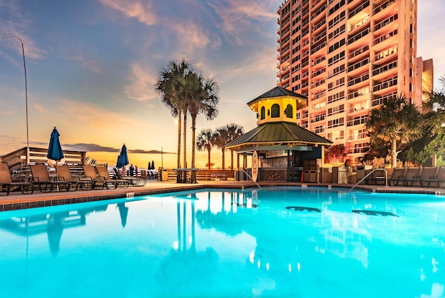 pool at dusk featuring a gazebo