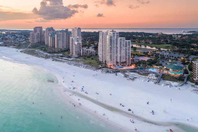 aerial view at dusk featuring a beach view and a water view