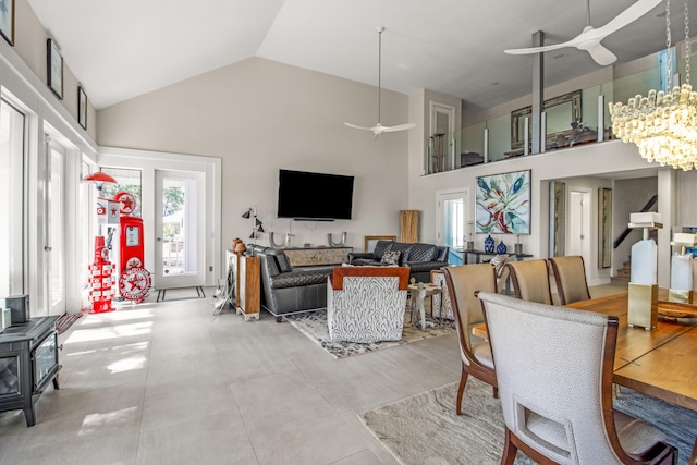 tiled living room with high vaulted ceiling and ceiling fan with notable chandelier